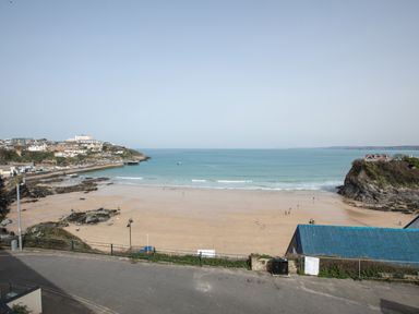 A sandy beach with a few people and houses on cliffs at Onshore 6 - Newquay Towan Beach View in Newquay