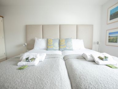 A bedroom with two beds joined together with white pillows and grey cushions at Onshore 6 - Newquay Towan Beach View in Newquay