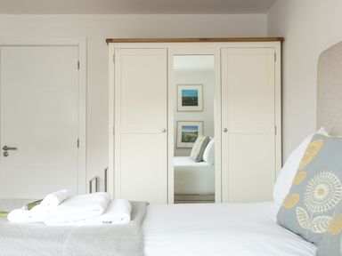 A bedroom with a bed pillow towels on the bed and a wardrobe with a mirror at Onshore 6 - Newquay Towan Beach View in Newquay