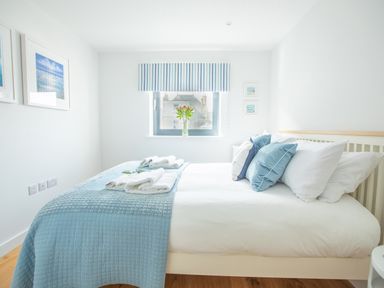 A bedroom with a bed with blue and white bedding and towels on top at Onshore 6 - Newquay Towan Beach View in Newquay