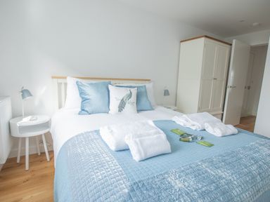 A bedroom with a bed covered in a blue quilt and white towels on top at Onshore 6 - Newquay Towan Beach View in Newquay