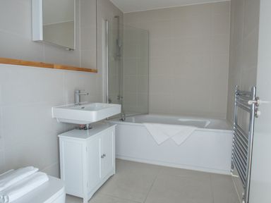 A bathroom with a sink cabinet and a bathtub with a shower screen at Onshore 6 - Newquay Towan Beach View in Newquay