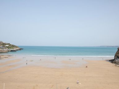 A sandy beach with people walking and the sea in the background at Onshore 6 - Newquay Towan Beach View in Newquay