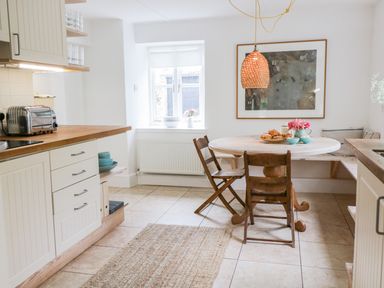 A kitchen with a round dining table two chairs a bench and a woven pendant light at Whitehall Farm Cottage Honiton