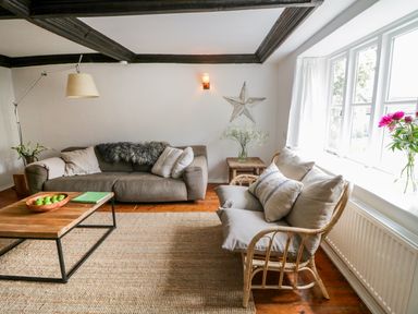 A living room with two sofas a wooden coffee table and large windows at Whitehall Farm Cottage in Honiton