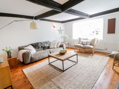 A living room with a sofa coffee table armchairs and wooden floor at Whitehall Farm Cottage in Honiton