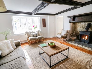 A living room with a fireplace wooden coffee table and cushioned seating at Whitehall Farm Cottage in Honiton