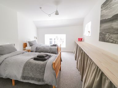 A bedroom with two single beds and a long wooden table with a skirt at Whitehall Farm Cottage in Honiton