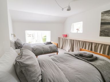 A bedroom with two beds covered in gray bedding and towels on each bed at Whitehall Farm Cottage in Honiton