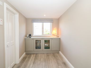 A small room with a window above a cabinet holding a kettle coffee machine and a sailboat lamp at 11 Marine Terrace in Criccieth