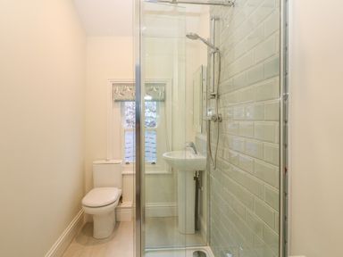 A bathroom with a toilet sink and shower area with tiled wall at 11 Marine Terrace in Criccieth