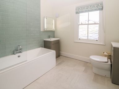 A bathroom with a bathtub sink toilet and window at 11 Marine Terrace in Criccieth