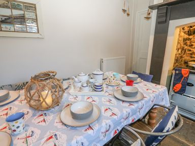 A dining table set with bowls plates cups and a lantern on a tablecloth with boats at 11 Marine Terrace in Criccieth