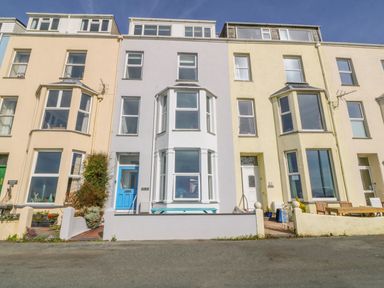 A row of multi-story terraced houses with bay windows and small front yards at 11 Marine Terrace in Criccieth