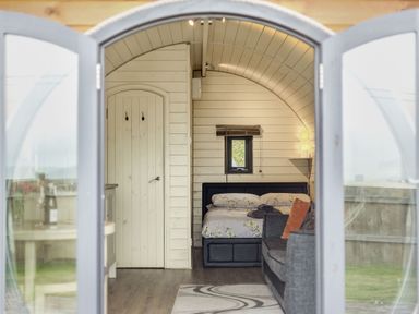 A view through open glass doors showing a bedroom with a bed and a couch at Corndon Pod White Grit near Chirbury