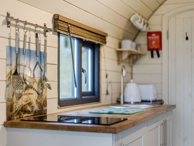 A kitchen counter with utensils hanging on the wall a window a sink a kettle and a toaster at Corndon Pod White Grit near Chirbury