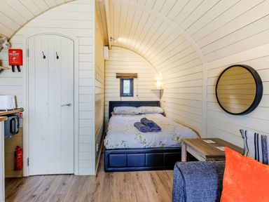 A bedroom with a bed towels mirror sofa and door at Corndon Pod in White Grit near Chirbury