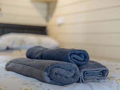Three folded towels on a bed with a headboard and wall panels at Corndon Pod in White Grit near Chirbury