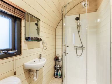 A bathroom with a corner shower enclosure sink mirror and a small shelf with towels at Corndon Pod in White Grit near Chirbury