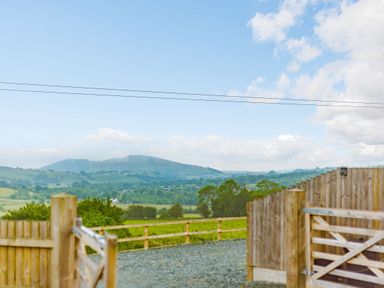 A rural landscape with a gravel path and wooden fences overlooking hills and fields at Corndon Pod in White Grit near Chirbury