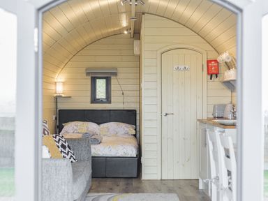 A small room with a bed sofa a wooden door and a kitchenette at Stiperstones Pod White Grit near Chirbury