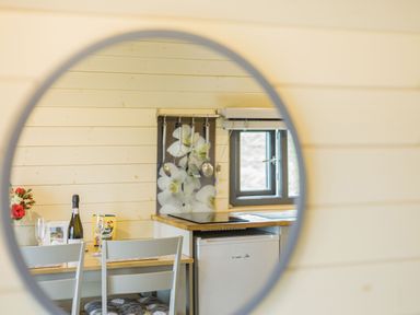 A small dining table with chairs a bottle of wine and glasses and a kitchenette with a fridge stove and utensils at Stiperstones Pod White Grit near Chirbury
