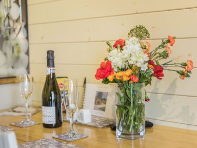 A table with a bottle of prosecco two glasses and a vase of flowers at Stiperstones Pod White Grit near Chirbury