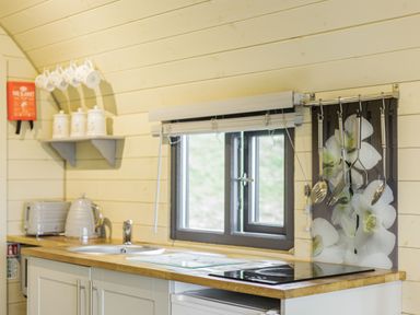 A kitchen area with a window above a countertop holding a sink stove kettle and toaster at Stiperstones Pod in White Grit near Chirbury