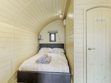 A bedroom with a double bed towels on the bed and a small window at Stiperstones Pod in White Grit near Chirbury