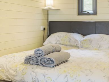 A bed with floral bedding and three rolled towels on top at Stiperstones Pod in White Grit near Chirbury