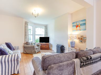 A living room with sofas a television a lamp and a painting at Downlea in Looe