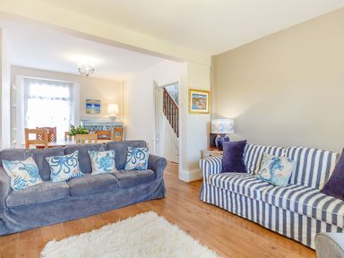 A living room with two sofas and a dining table in the background at Downlea in Looe