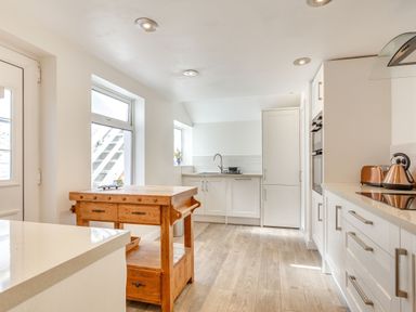 A kitchen with white cabinets wooden island and copper kettle and toaster at Downlea in Looe