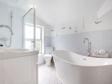 A bathroom with a freestanding bathtub a toilet a sink a shower and decorative items on the wall at Downlea in Looe