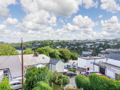 A hillside view of houses cars trees and a cloudy sky at Downlea in Looe