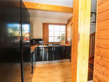 A kitchen with black appliances wooden countertops wooden floors and a window with blinds at Swallow Lodge in Amble