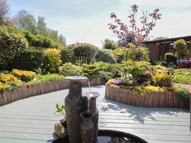A garden with a water feature and various plants and shrubs at Swallow Lodge in Amble