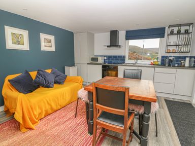 A kitchen and dining area with a yellow covered sofa and three black cushions at Haka Lodge in Devil's Bridge