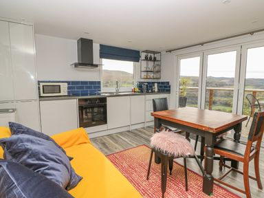 A kitchen and dining area with a yellow sofa and blue cushions at Haka Lodge in Devil's Bridge