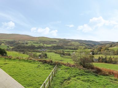A green valley with hills trees and scattered houses at Haka Lodge in Devil's Bridge