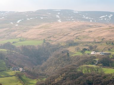 A rural landscape with hills trees and houses at Haka Lodge in Devil's Bridge