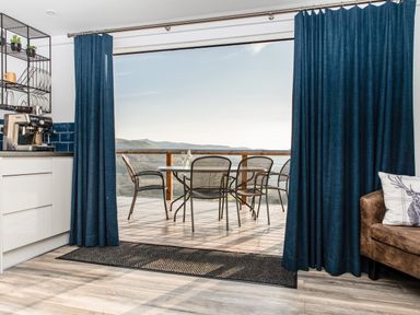 A kitchen with coffee machine and open sliding door leading to outdoor dining area with table and chairs at Haka Lodge in Devil's Bridge