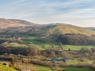 A rural landscape with hills trees and farm buildings at Haka Lodge in Devil's Bridge