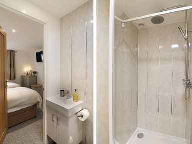 A small bathroom with a sink and paper holder next to a shower area with a handheld shower at Upham View in Woodbury