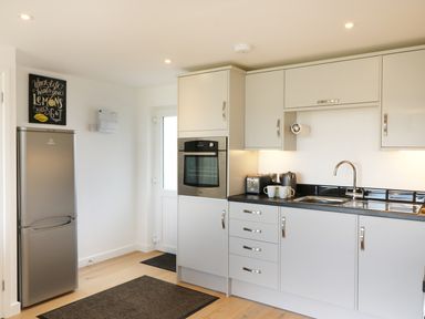 A kitchen with grey cabinets a silver fridge an oven a sink and a countertop with a toaster kettle and mugs at Upham View in Woodbury