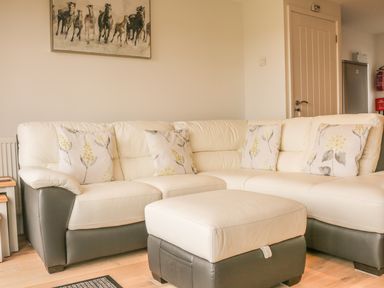 A living room with a sectional sofa with floral cushions and a matching ottoman at Upham View in Woodbury