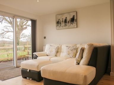 A living room with a beige and black sectional sofa and horse painting on the wall at Upham View in Woodbury