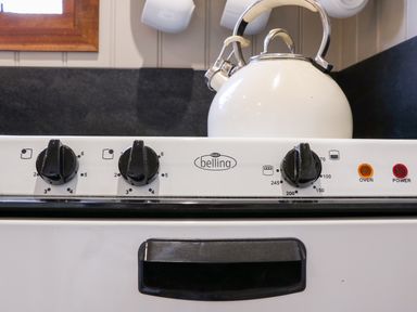 A stove with control knobs and a kettle on the back at Little Silver Fox in High Bickington
