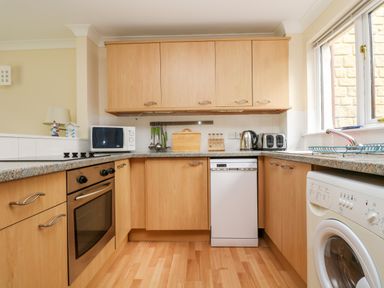 A kitchen with wooden cabinets appliances and countertop near a window at Pugwash Cottage in Falmouth