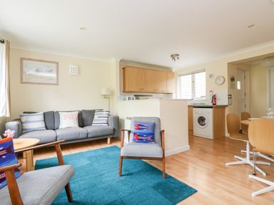 A living room with a sofa and chairs next to a kitchen and dining area at Pugwash Cottage in Falmouth